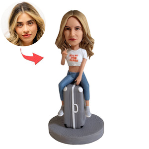 Figura cabezona personalizada sentada en una maleta