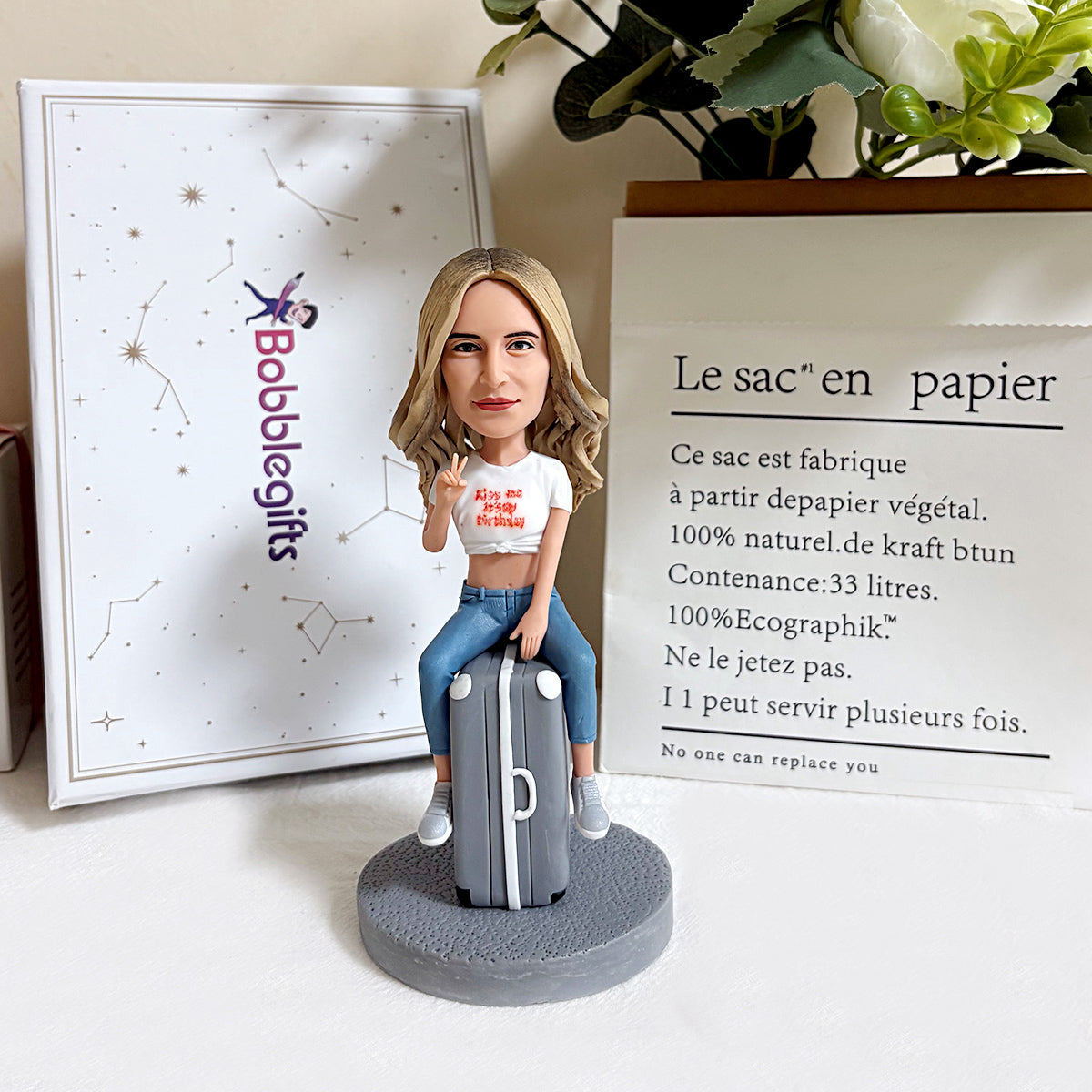 Figura cabezona personalizada sentada en una maleta
