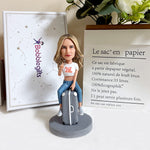 Figura cabezona personalizada sentada en una maleta