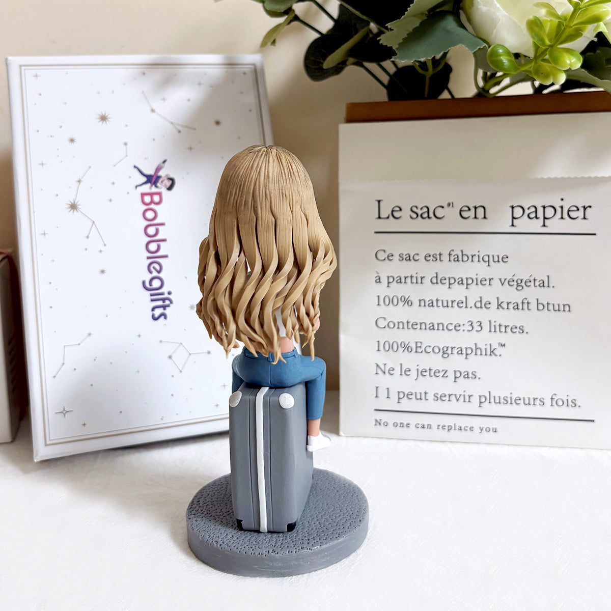 Figura cabezona personalizada sentada en una maleta