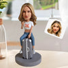 Figura cabezona personalizada sentada en una maleta
