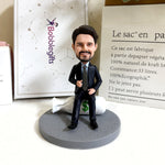 Muñeco cabezón personalizado con traje sentado sobre una bolsa de dinero.