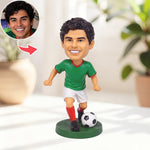 Figura cabezona personalizada de un jugador de fútbol pateando un balón.