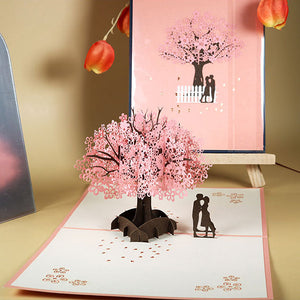 Tarjeta de felicitación emergente 3D de pareja romántica bajo el cerezo