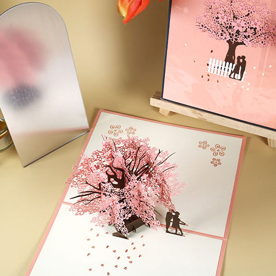 Tarjeta de felicitación emergente 3D de pareja romántica bajo el cerezo